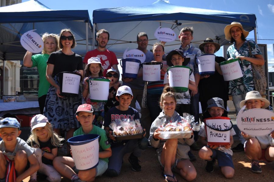 Parents+and+students+at+the+NESSA+launch+in+front+of+a+fundraising+stall.+Their+buckets+illustrate+how+much+money+they+need+to+raise+every+year+for+basic+school+services.