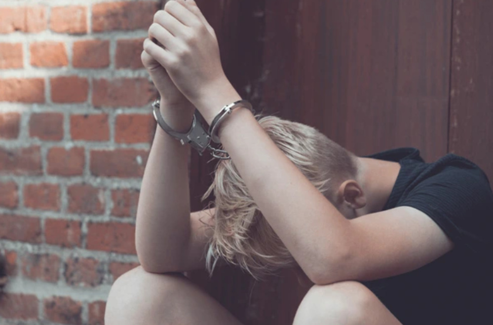 a young child in handcuffs with their head down