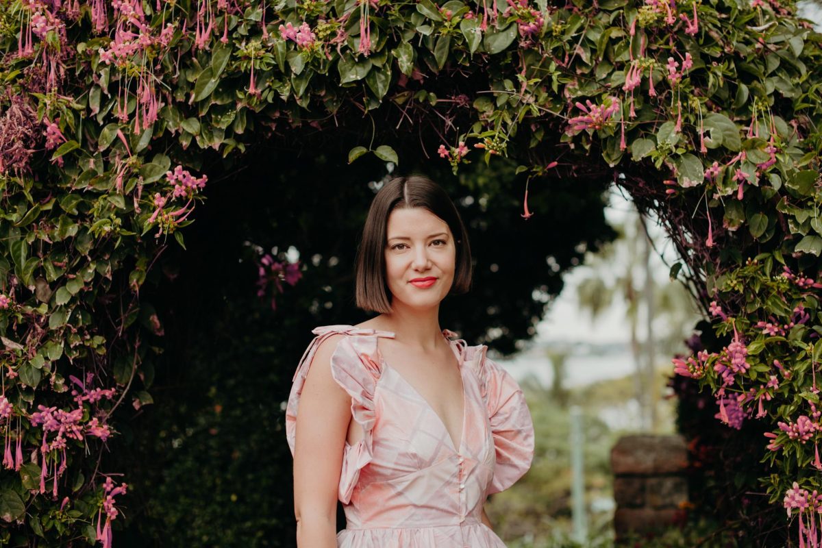 A woman wearing a pink dress standing in front of a flower