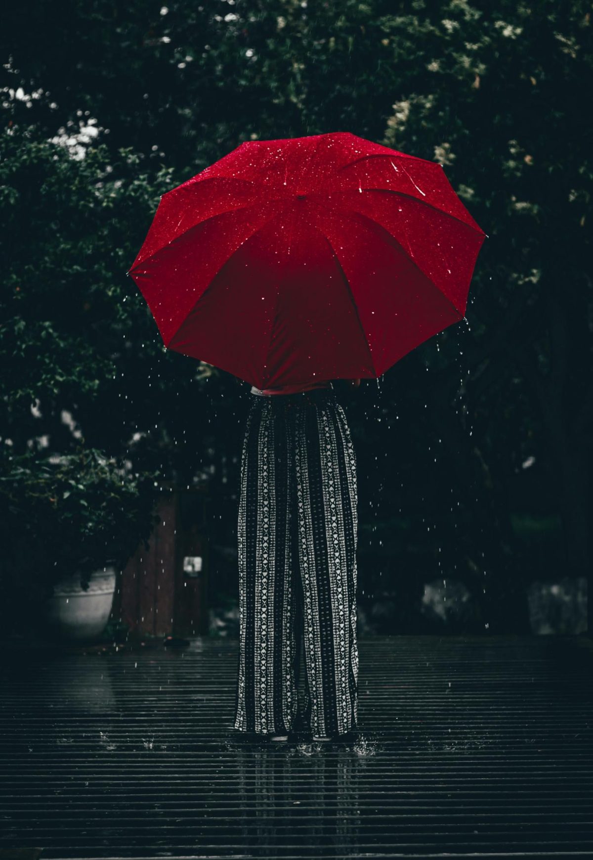 A woman standing in the rain holding an umbrella
